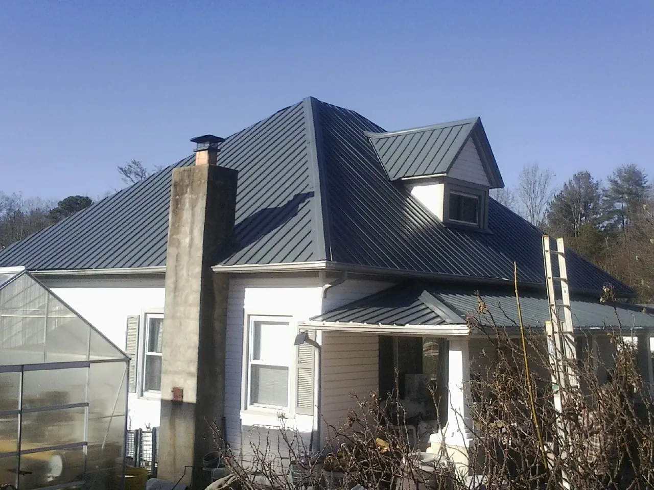Dark blue standing seam metal roof on a white farmhouse with dormer — Slate & Tile Roof Repair by Roofing Brothers in Sterling Forest