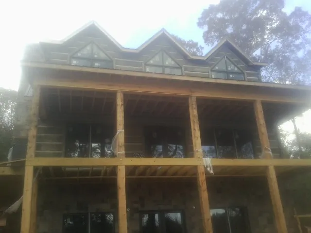 Dormers and porch framing on a large log home under construction — Roof Coating work by our crew in Sterling Forest