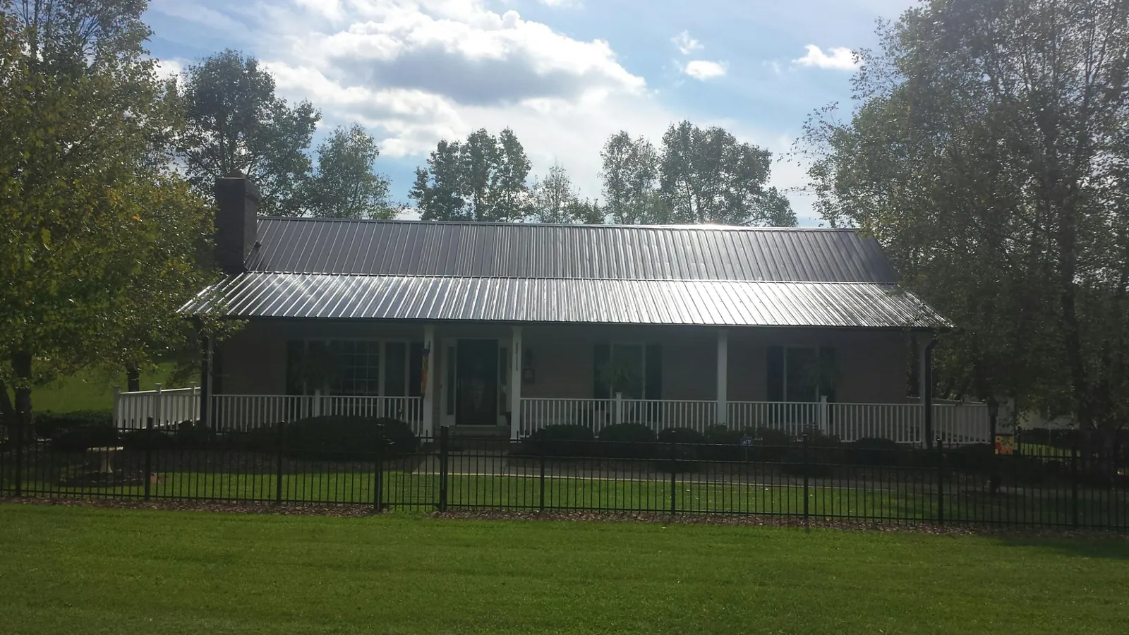 Gray metal roof on a brick ranch with a full width front porch — Gutter Guard Installation work by our crew in Sterling Forest