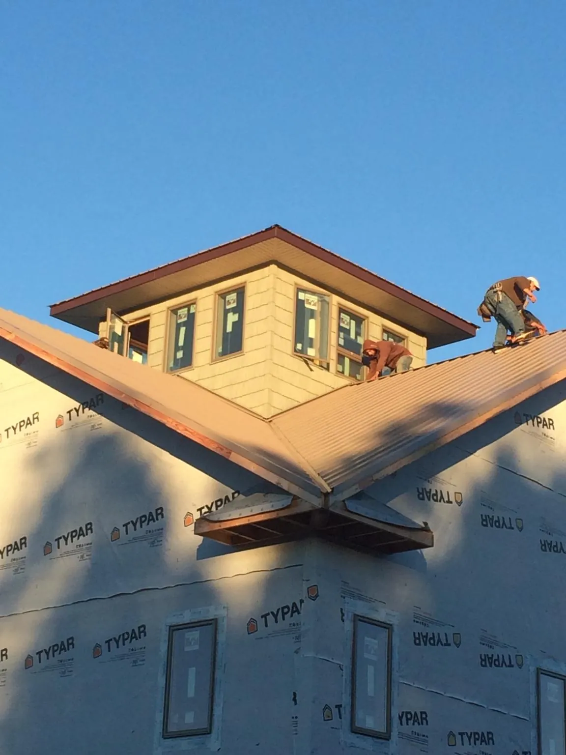 Roofers working around a rooftop cupola on a new metal roof at sunset — Roof Waterproofing in Sterling Forest by Roofing Brothers